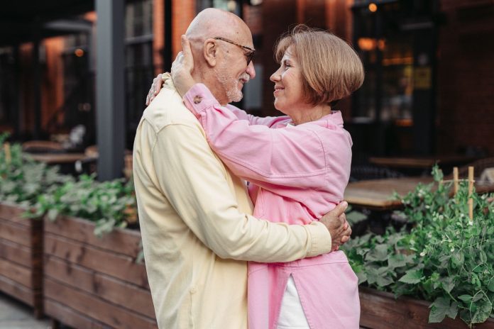 Elderly couple lovingly embracing outdoors, showcasing happiness and togetherness.