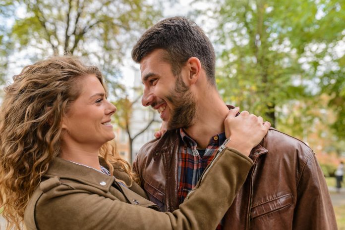 Happy couple enjoying a romantic moment outdoors, embracing and smiling at each other.