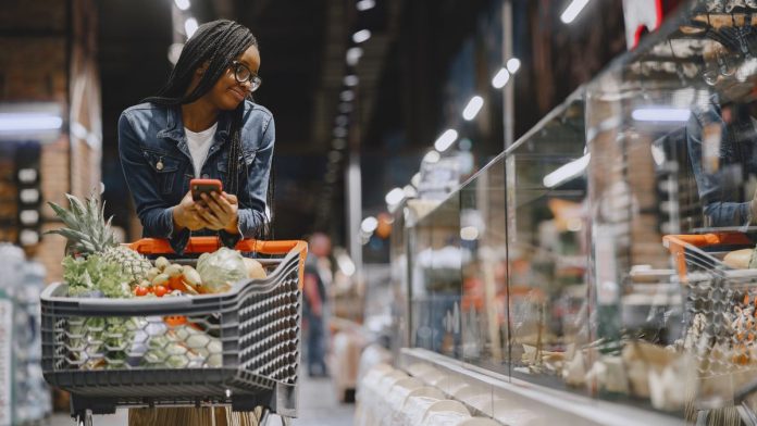 Woman reading a food package label while grocery shopping
