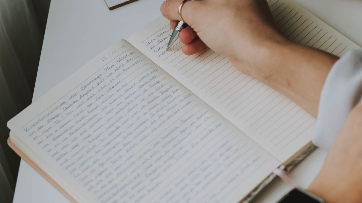 Person writing in a notebook to track workouts and stay motivated to exercise