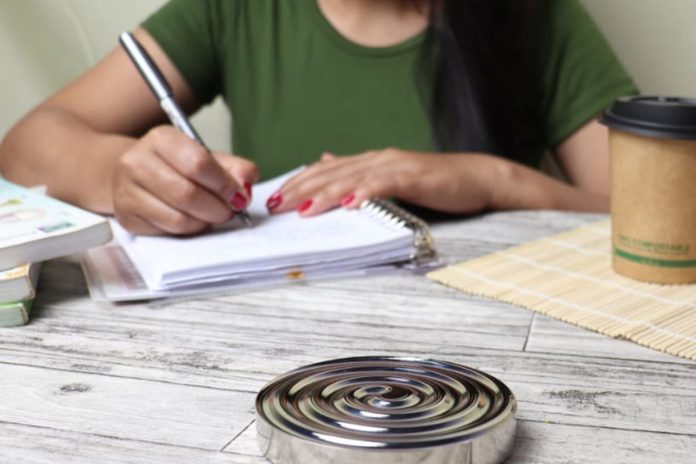 Woman writing weight-loss goals in a notebook at a desk