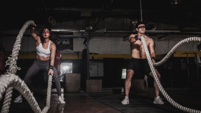 Man and woman training with battle ropes during a HIIT workout