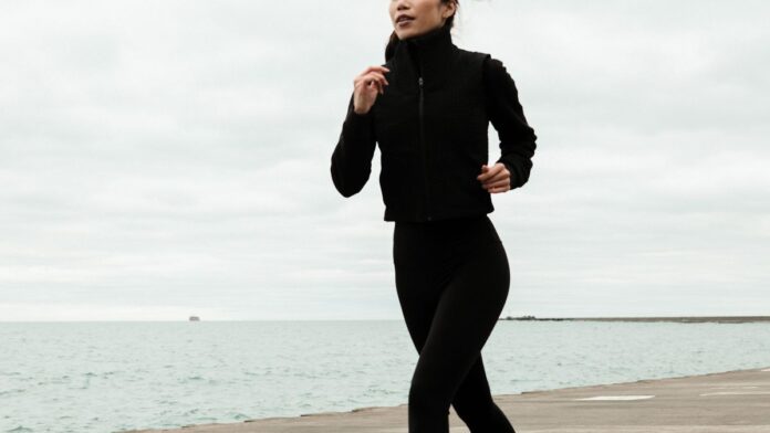 Woman jogging outdoors near a waterfront, staying motivated to exercise