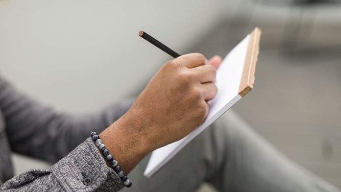 Woman sitting by a window writing in a journal