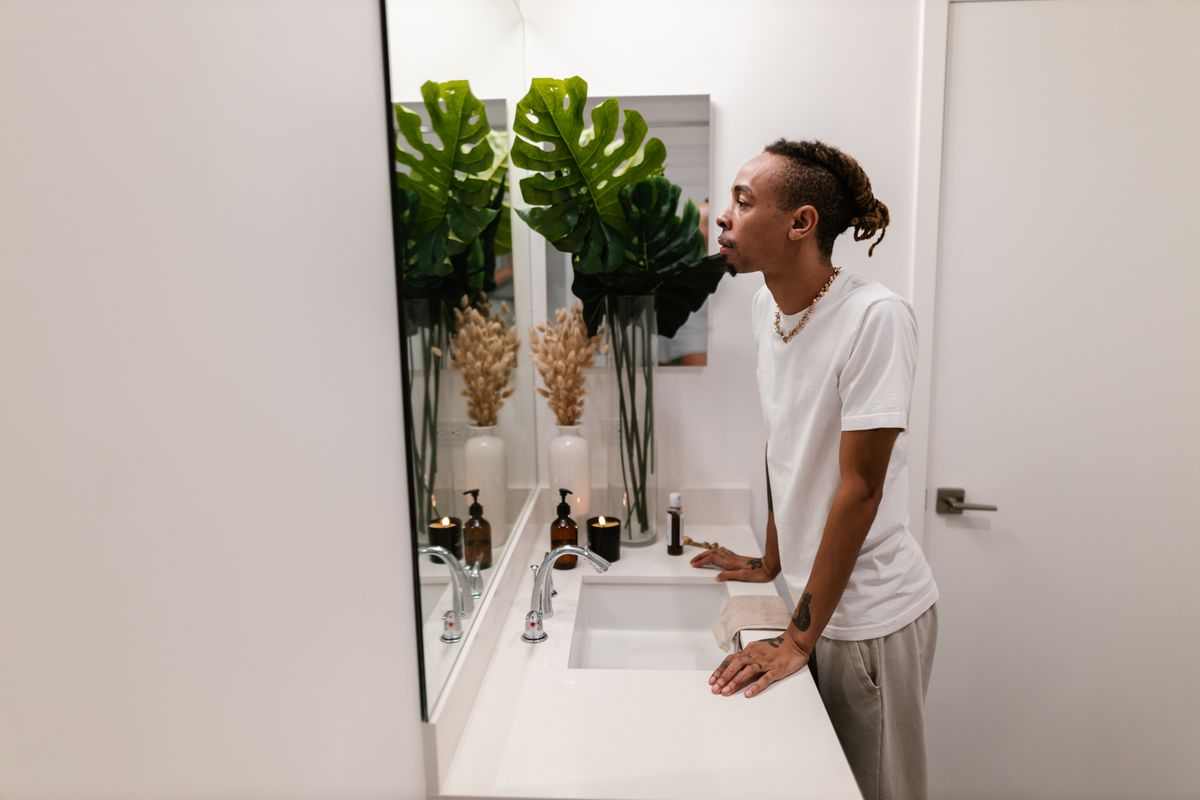 Man examining his hair and scalp in a bathroom mirror