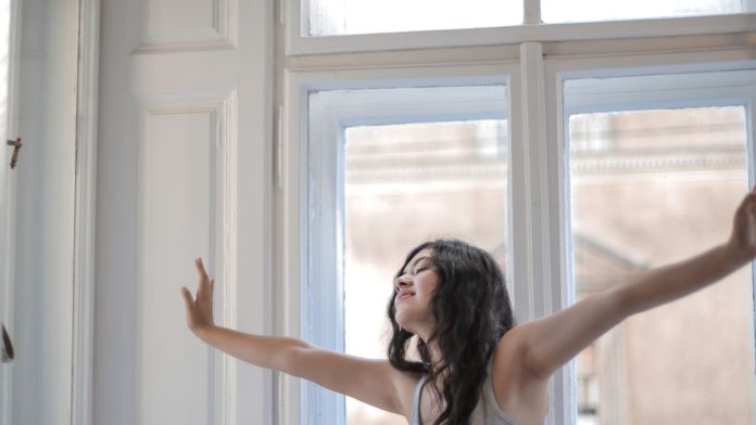 Woman waking up to bright morning light by a window
