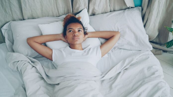 Thoughtful woman lying in bed, reflecting on painful sex and intimacy concerns
