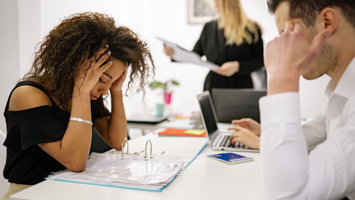 Overwhelmed woman at an office desk taking on too many requests from others