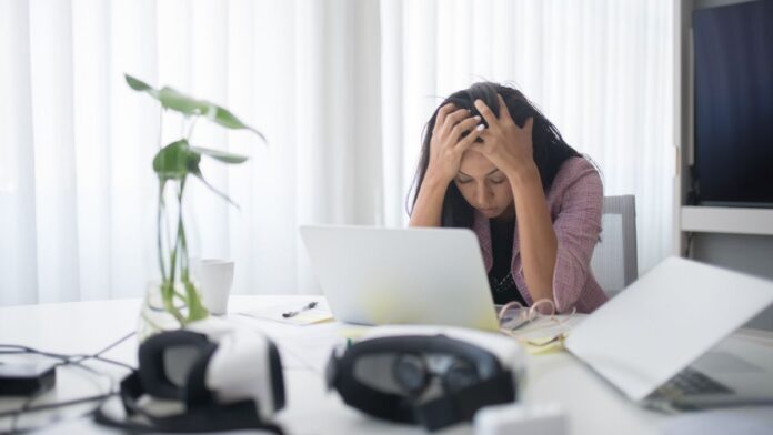 Stressed woman at work overwhelmed by saying yes to everything, a sign of people-pleasing