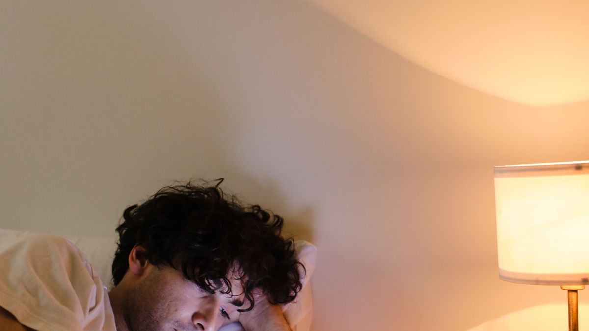 A man lying in bed using his phone late at night