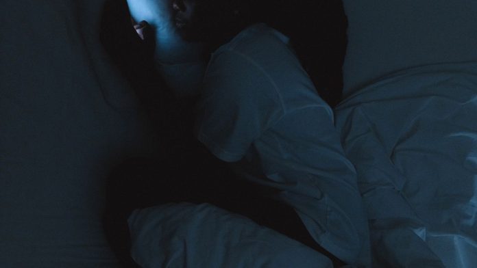 Woman using her phone in bed at night before sleep