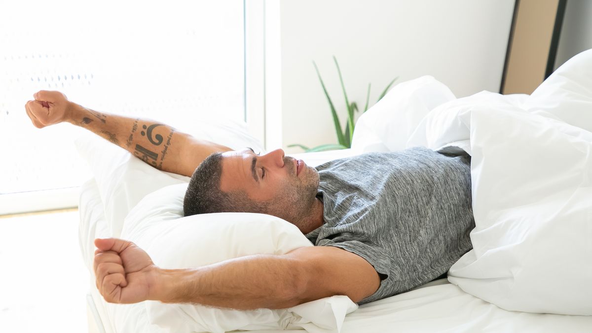 Man waking up refreshed in bed after treating sleep apnea