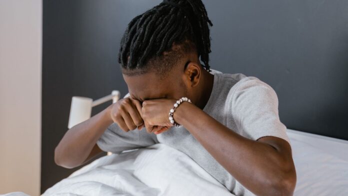 Tired man rubbing his eyes after waking up, a common sign of sleep apnea