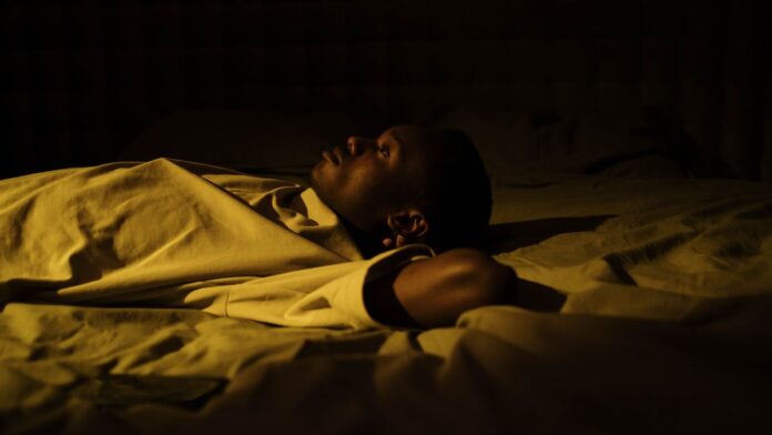 A tired man lying awake in bed at night, unable to sleep