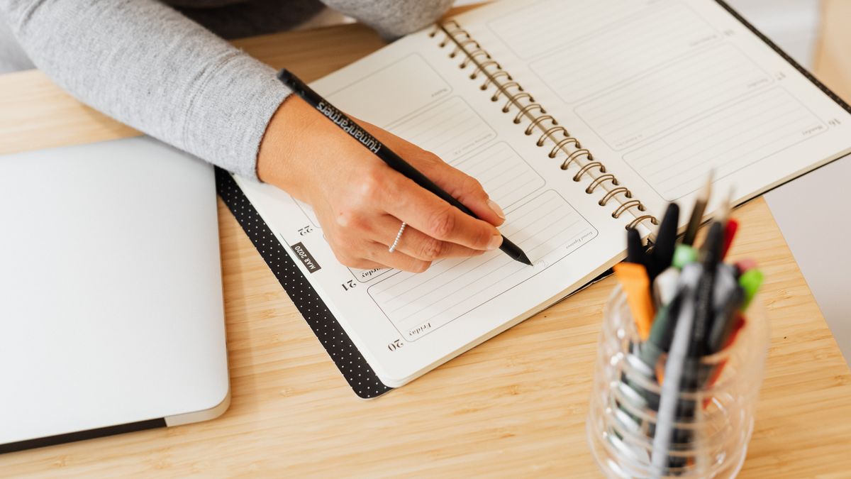 Person writing a diet break plan with a start and end date in a planner