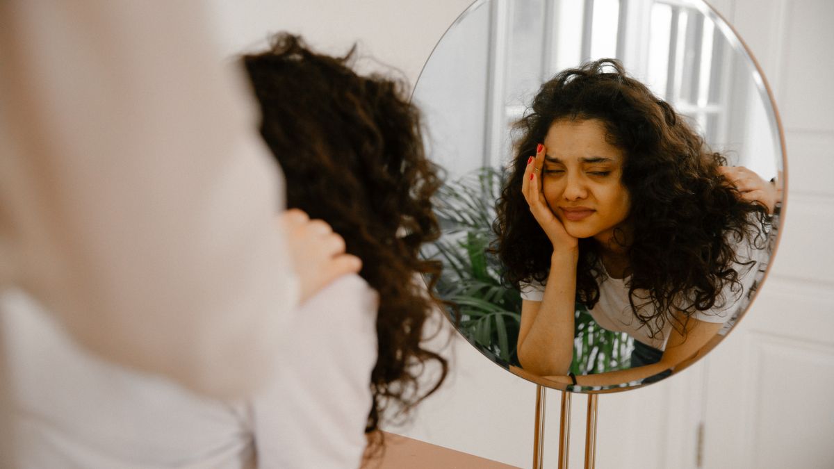 Woman reflecting on self-doubt and imposter syndrome in a mirror