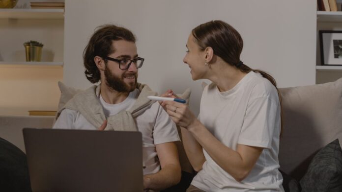 Happy couple sitting together looking at a positive pregnancy test