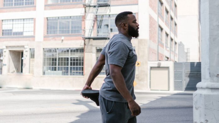 Man stretching his leg outdoors after a workout to ease muscle soreness