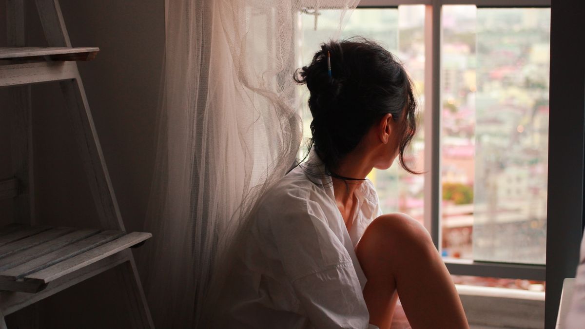 Woman sitting by a window in soft daylight during winter months
