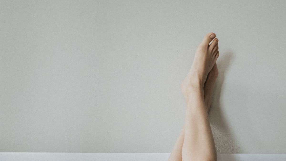 Person stretching their legs against a wall as part of an evening routine