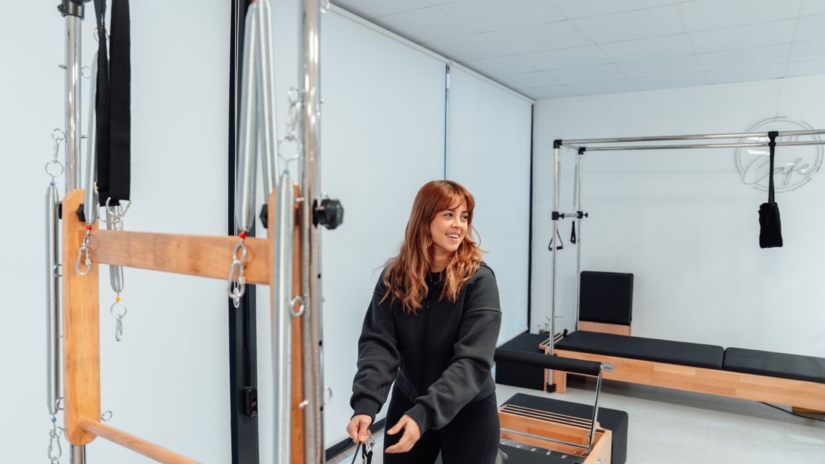 Woman strengthening her pelvic floor and core on a Pilates tower