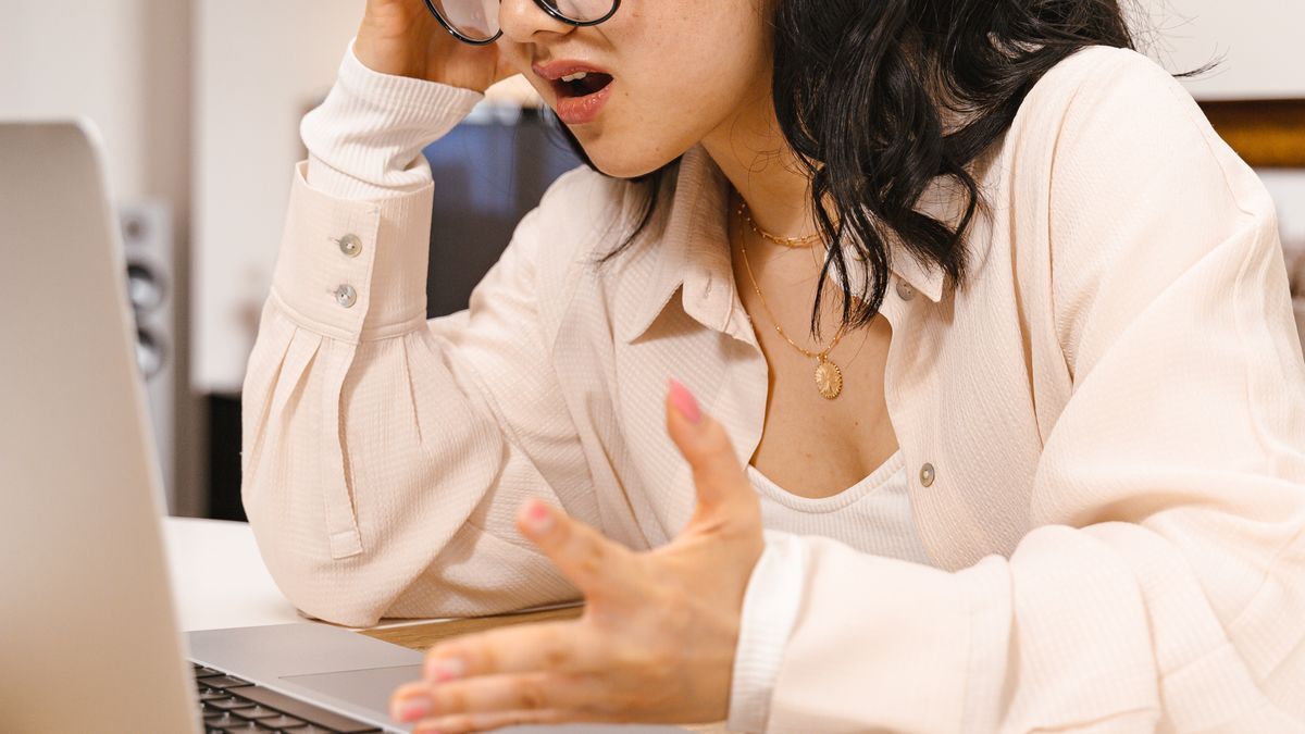 Frustrated perfectionist woman rereading her work at a laptop