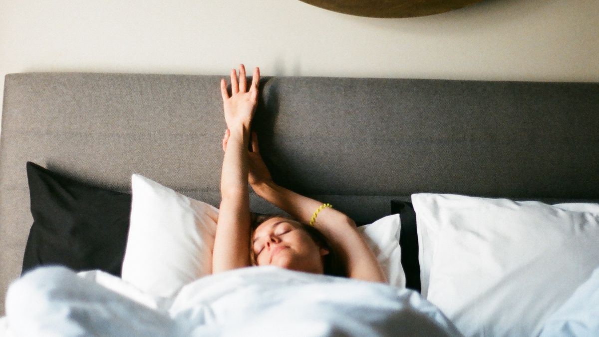 Woman stretching in bed after a good night of sleep tracked by her device