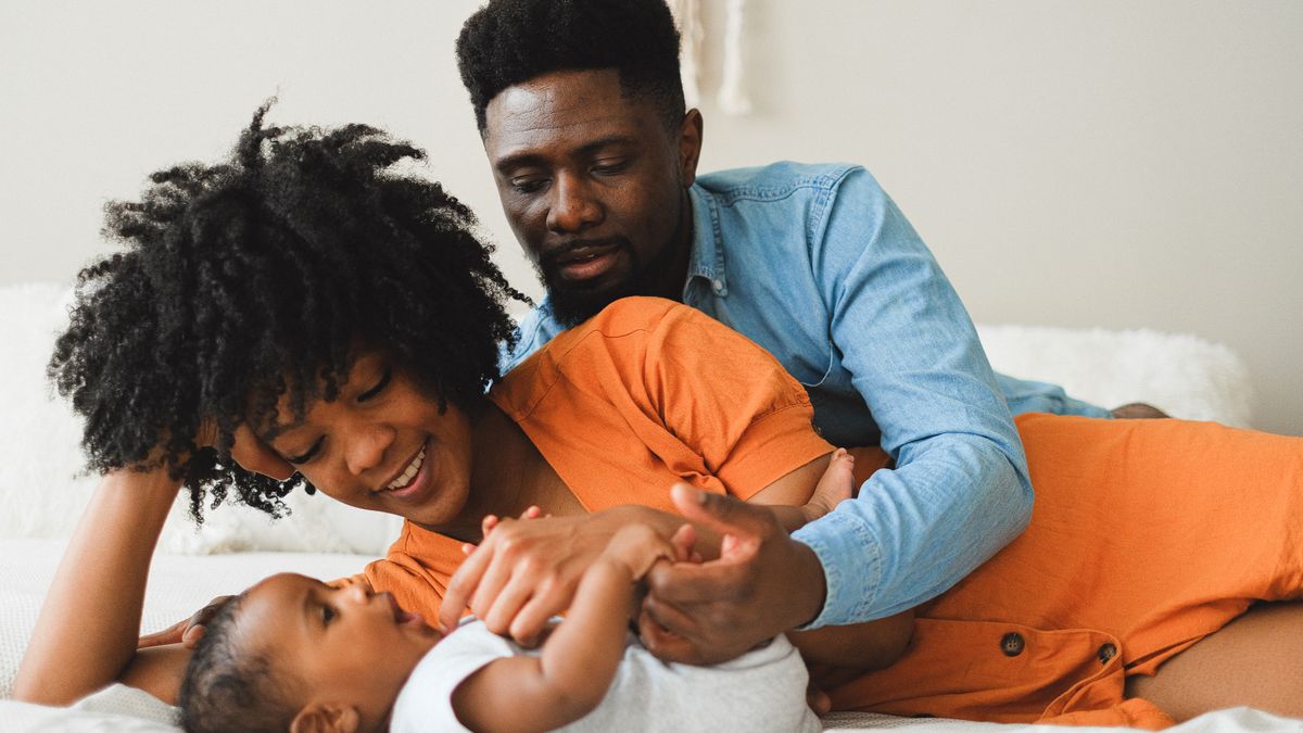 Mother and father leaning close together looking at their baby, reconnecting as a couple