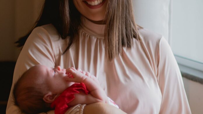New mother holding her newborn baby in soft natural light at home