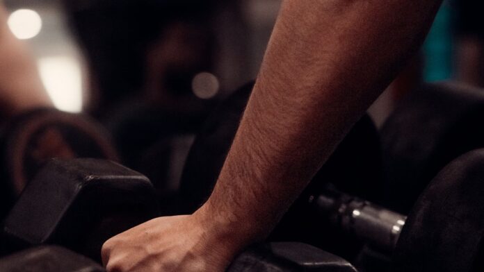 Focused hand gripping a dumbbell in the gym, building grip strength