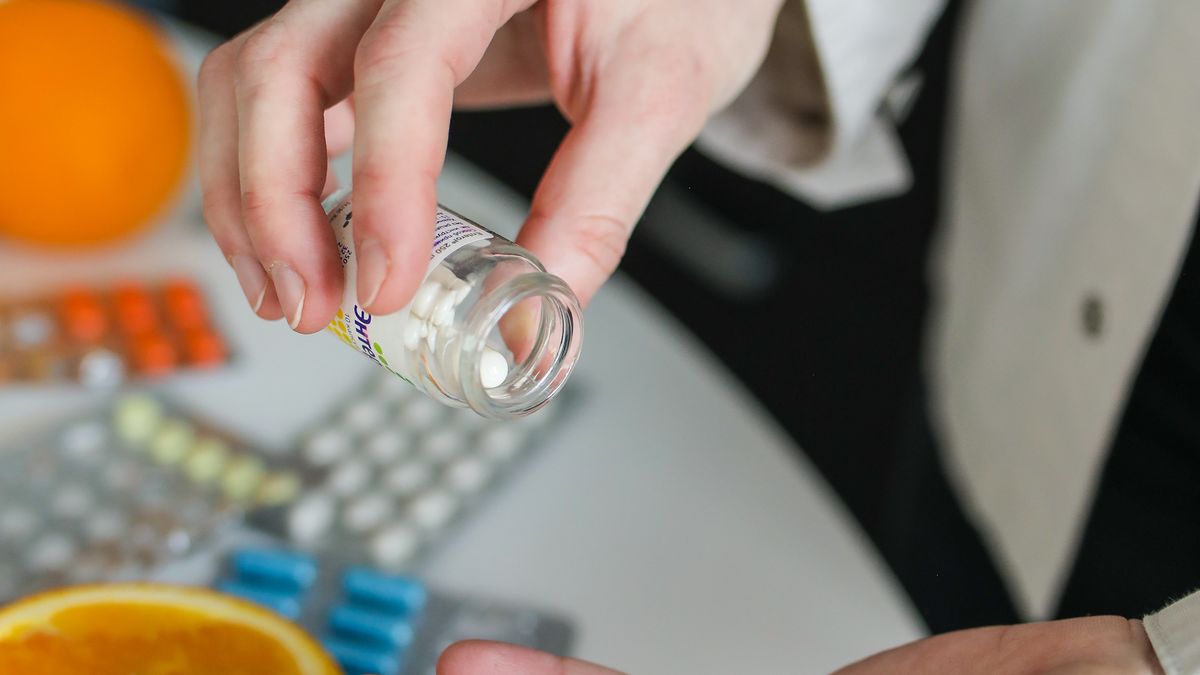 Person taking a vitamin D supplement capsule with a glass of water