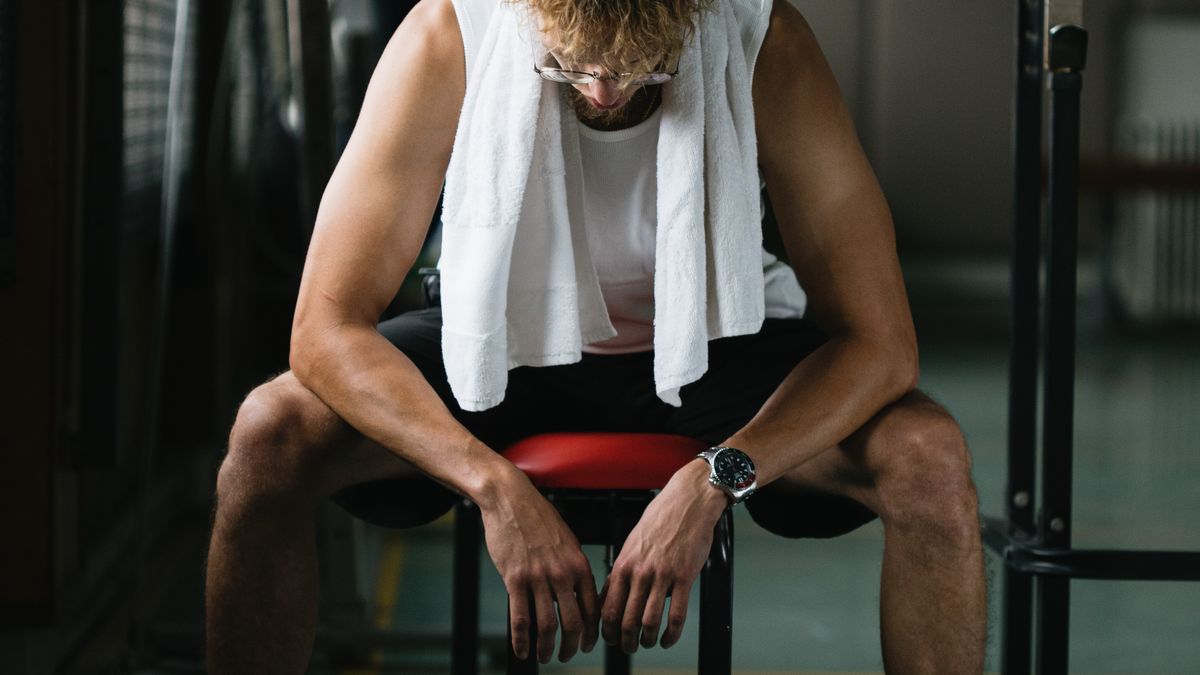 Exhausted male athlete resting on a bench after training in hot weather