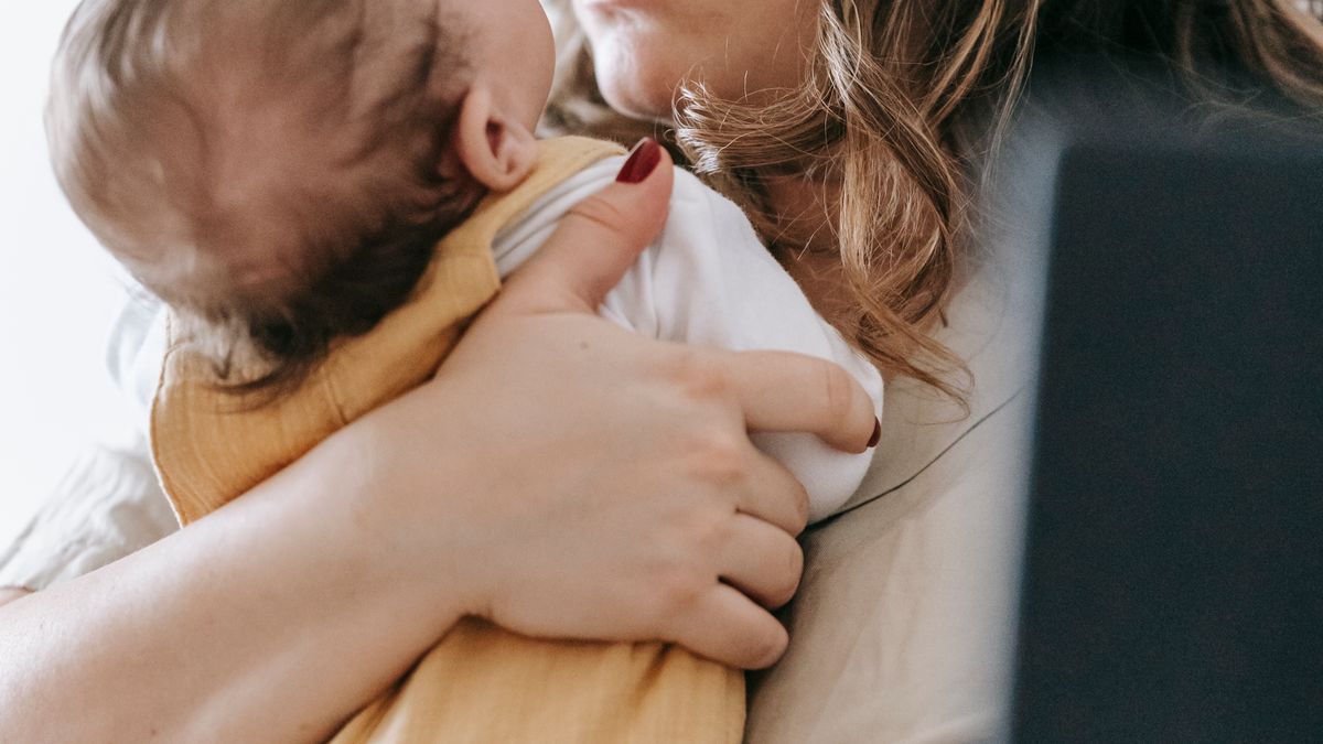 Tired new mother holding her infant, reflecting the exhaustion that affects sex after baby