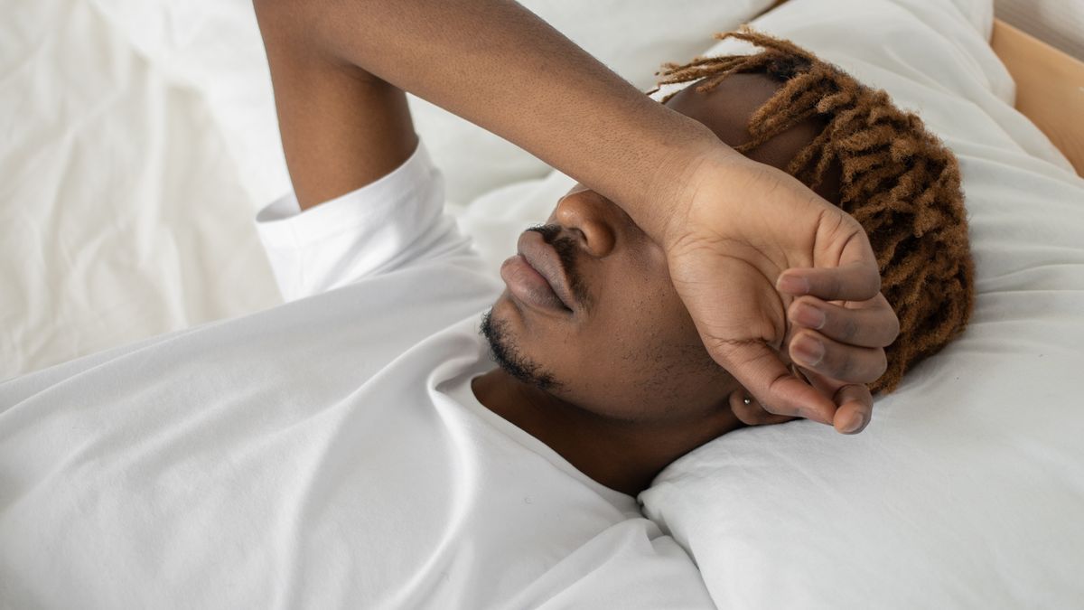 Person sleeping soundly in bed with a sound machine on the nightstand