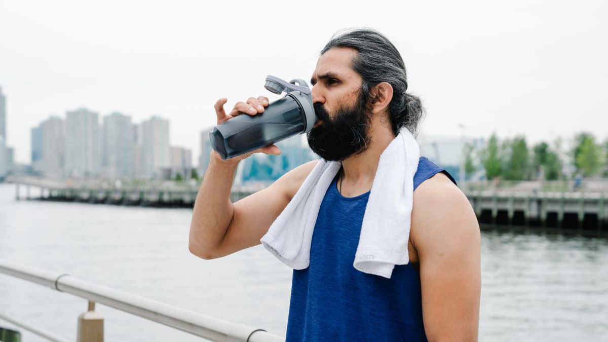 Man drinking water from a bottle after a hot outdoor workout