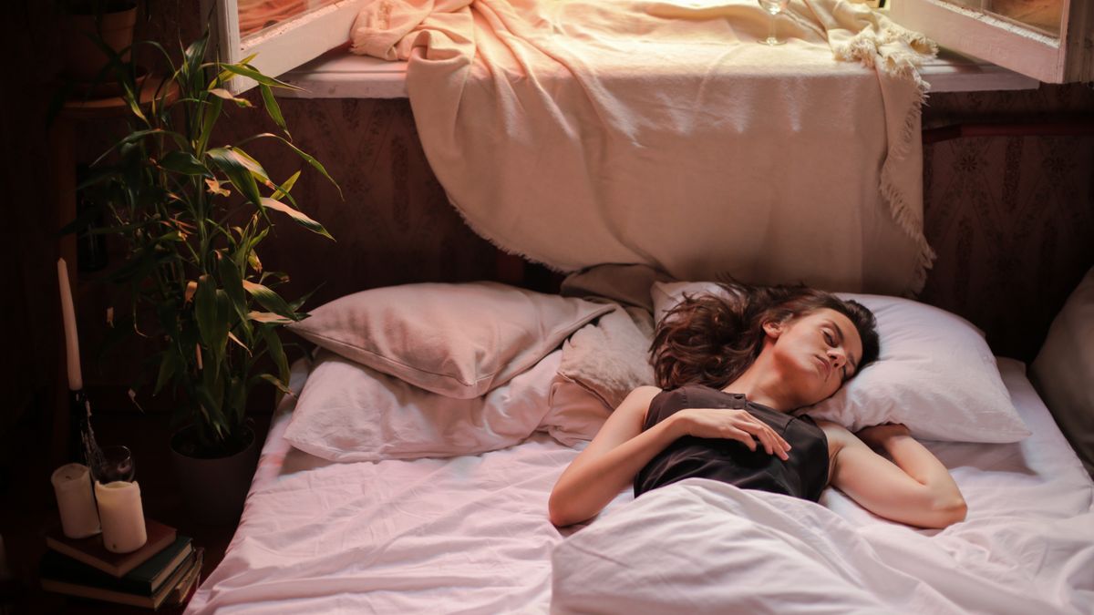 Woman sleeping alone in bed, resting undisturbed after a sleep divorce