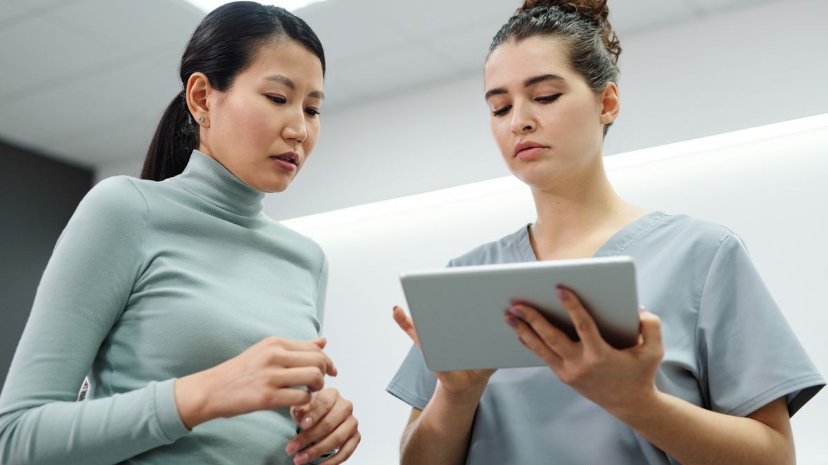 Doctor and patient reviewing information on a tablet during a women's health consultation