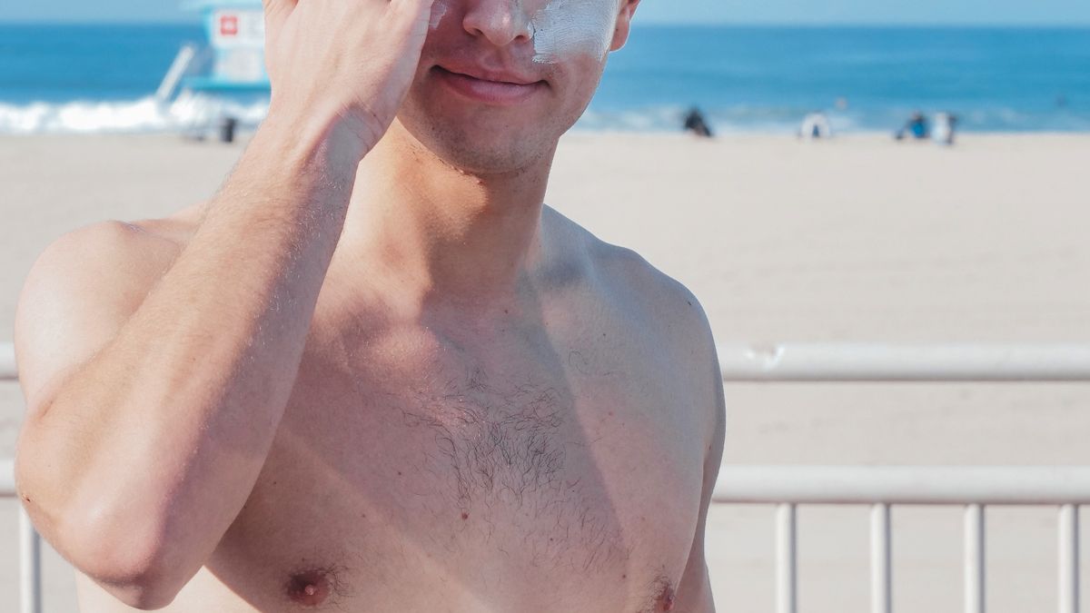 Man applying sunscreen to his face before going outside to help prevent skin cancer