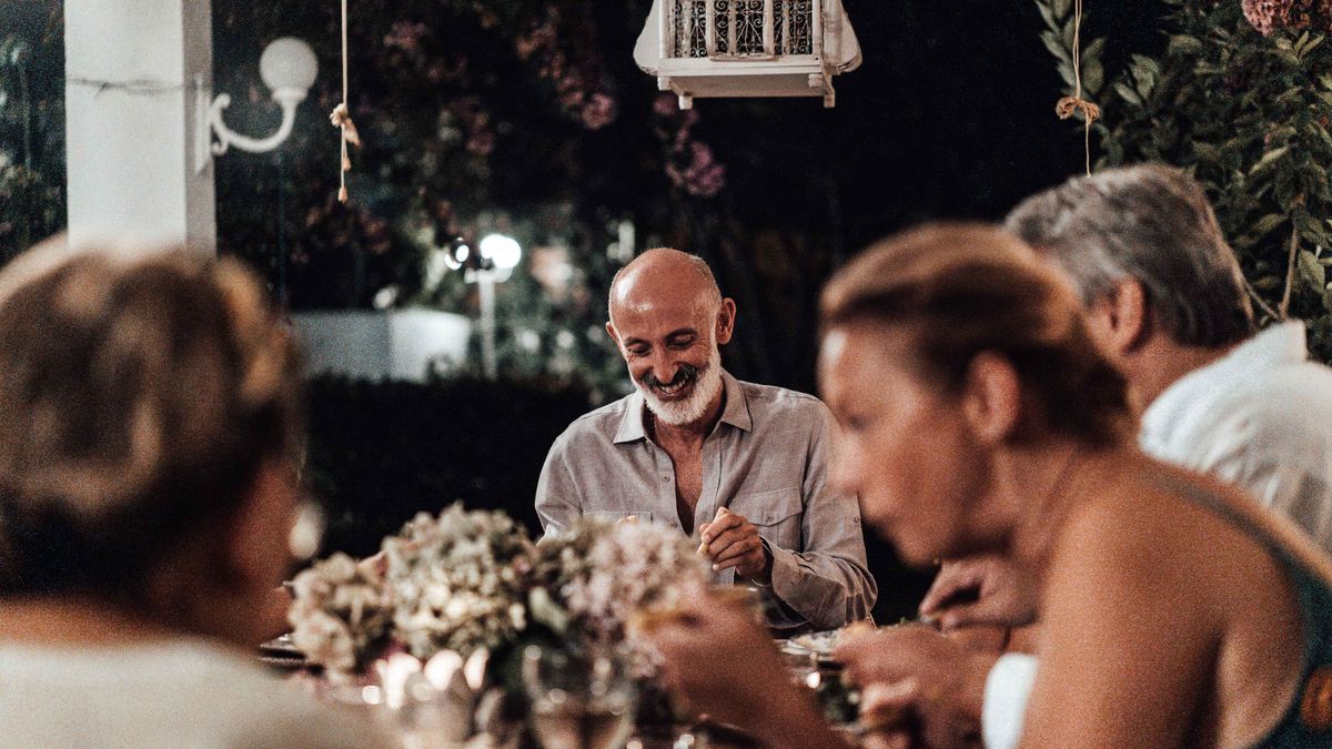 Friends eating dinner together at a warmly lit table in the evening