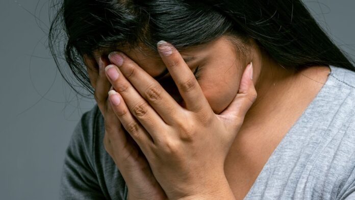 Woman hiding her face in her hands, masking difficult emotions behind toxic positivity