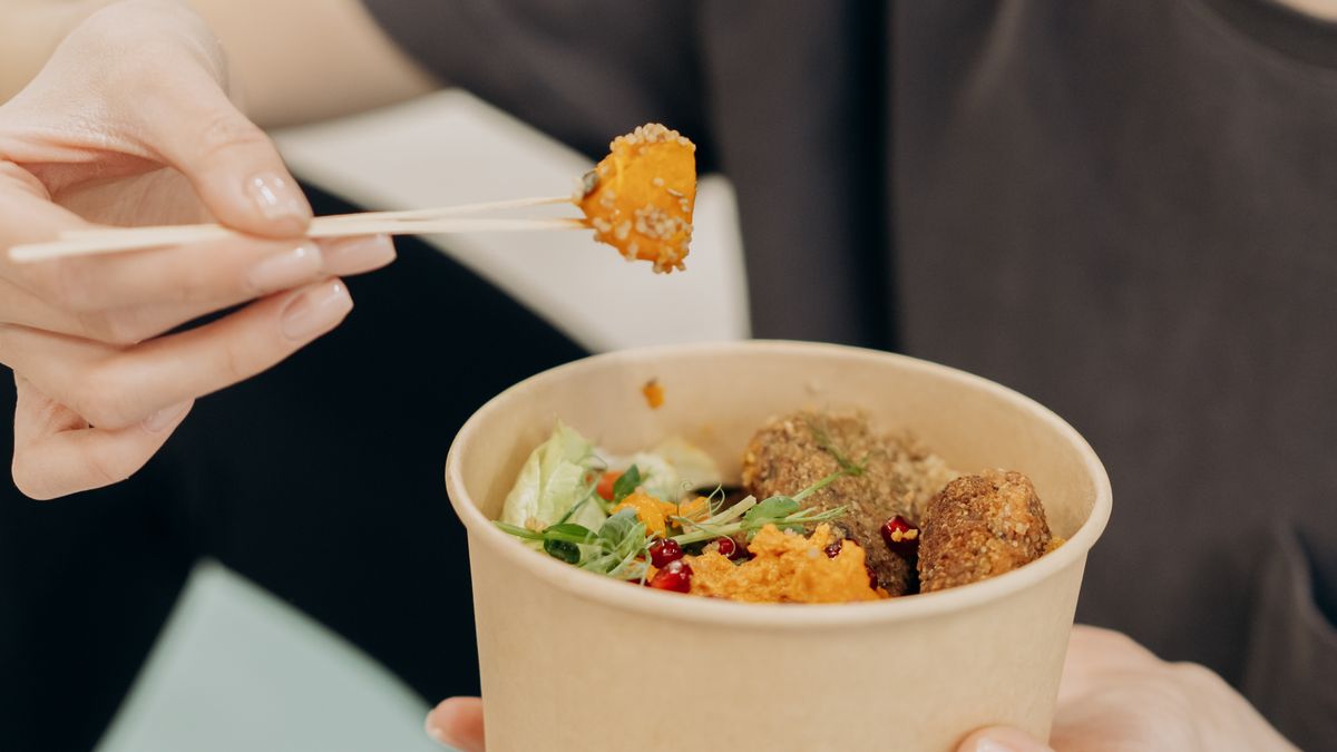 Woman eating a healthy bowl of food, illustrating how meals affect daily weight fluctuation